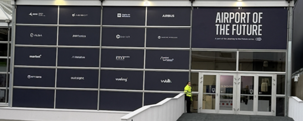 Entrén till Airport of the Future-zonen vid södra ingången till Fira de Barcelona. På fasaden syns samtliga partners – från Airbus och AENA till Outsight, NTT Data och Vueling. Zonen är en del av MWC:s "Journey to the Future"-serie, med flyg som första bransch. Foto: Nicholas Christiansen.