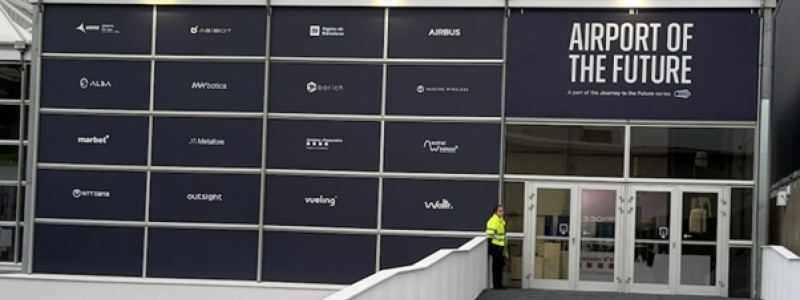 Entrén till Airport of the Future-zonen vid södra ingången till Fira de Barcelona. På fasaden syns samtliga partners – från Airbus och AENA till Outsight, NTT Data och Vueling. Zonen är en del av MWC:s "Journey to the Future"-serie, med flyg som första bransch. Foto: Nicholas Christiansen.
