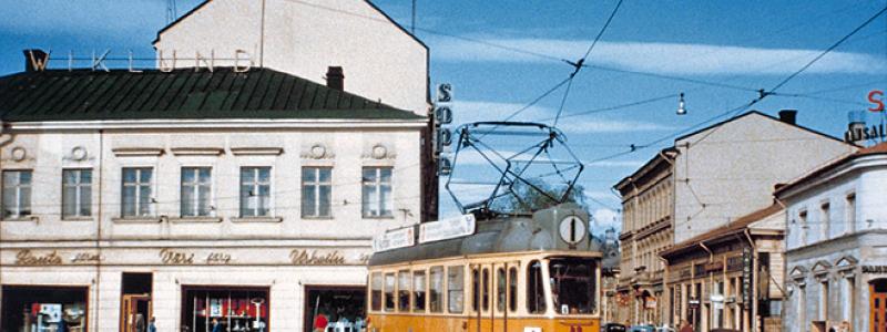 Spårvagn på Salutorget i Åbo 1959. Spårvagn nummer 49 av typen Valmet RM 2 trafikerade linje 1 när den år 1959 fotograferades vid Salutorget i Åbo. På bilden svänger vagnen i sydostlig riktning från Köpmansgatan in på Eriksgatan. Spårvägen lades ner 1972 och bussarna fick ta över transporterna. Foto: Okänd – stadinratikat.fi vid Wikipedia Common Lic.