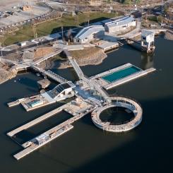 Hamnbadet i Jubileumsparken, Frihamnen 7 i Göteborg. Två naturvattenpooler och en sötvattenpool med naturlig rening, flytande ytan totalt ca 1008 m² och bassängerna sammanlagt ca 580 m². Befintliga pontoner och bassäng har återanvänts. Pontonerna är exceptionellt stora, gjutna och levererade på sänkbar pråm. Speciellt för hamnbadet är också diamantformade pontonen i mitten och den runda pontonen med hopptorn utanpå. Foto: Bluet