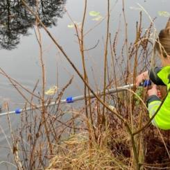 En vattenhämtare med teleskopspinne används för att samla in vattenprover en bit ut från strandkanten. Proverna skickas sedan till laboratorium för analys. Foto: Trafikverket